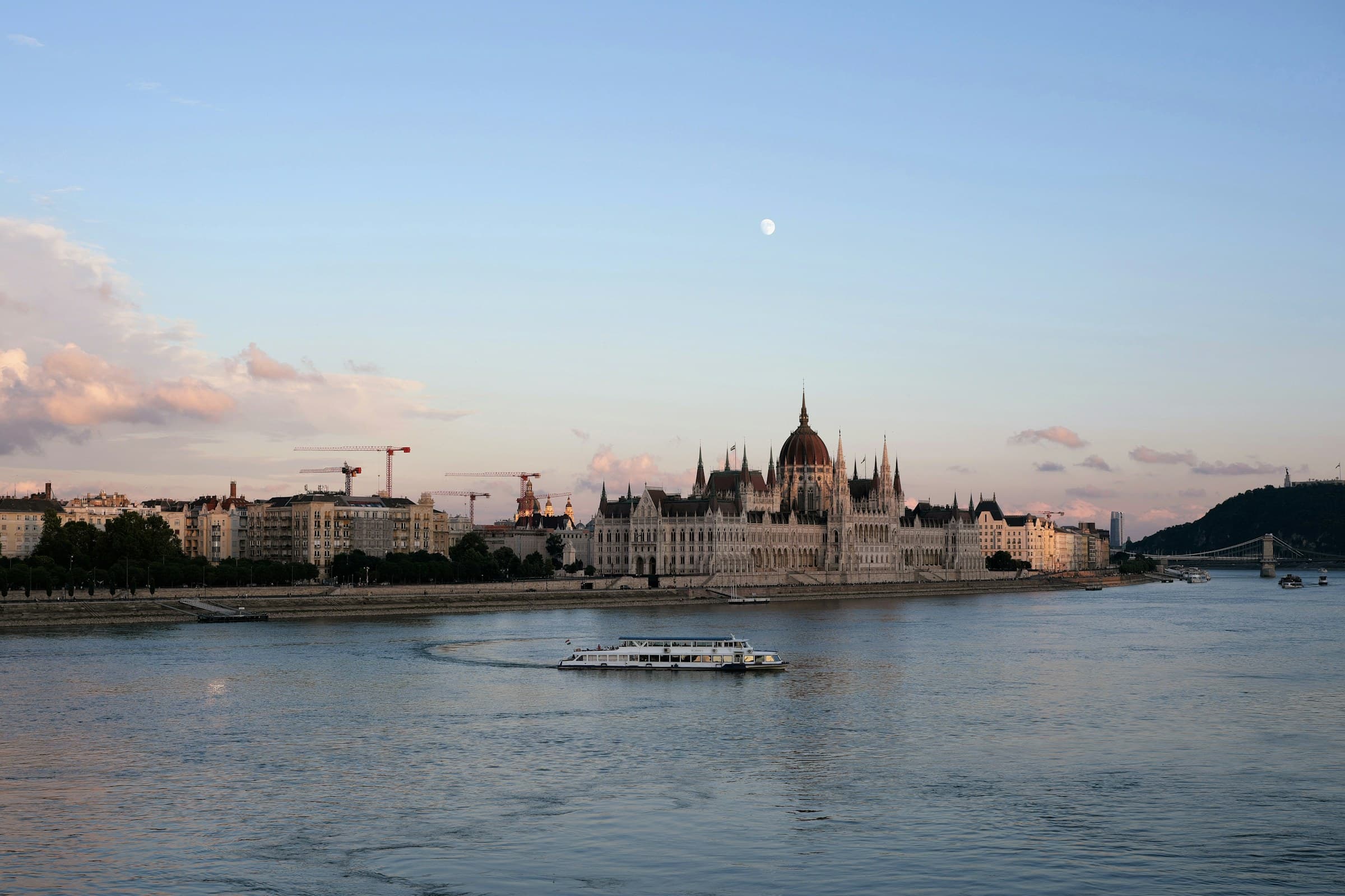 A sightseeing boat passes the Hungarian Parliament building on the Danube at dusk